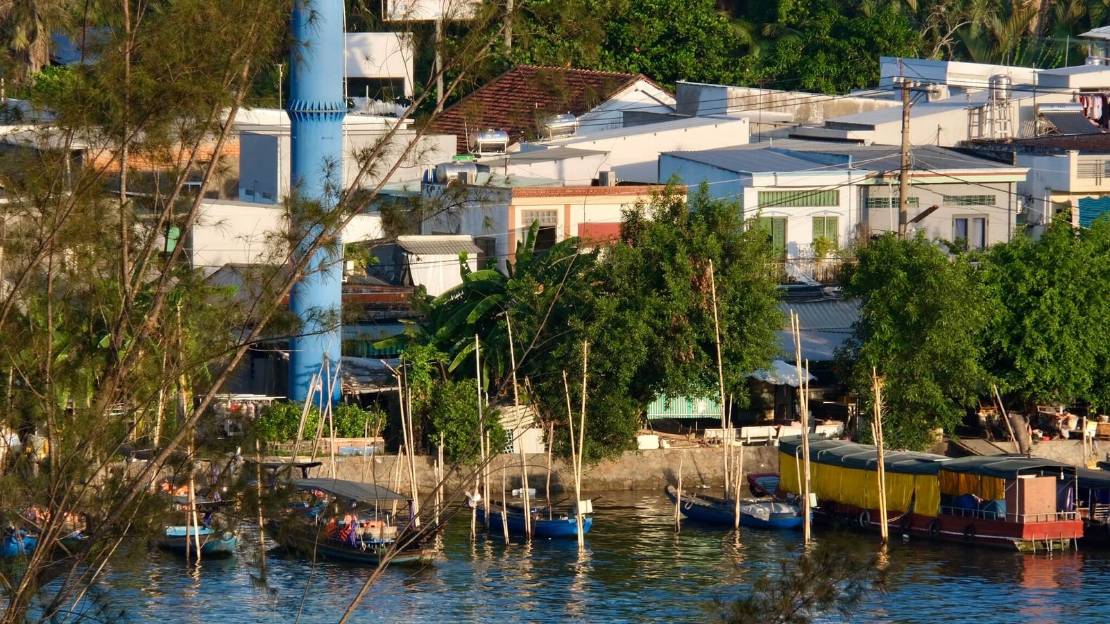 Early morning light on a riverside neighbourhood across the water from Ninh Kiều, Cần Thơ, with wood