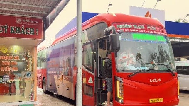 A red Phương Trang Futa Buslines coach pulled into a station bay in daylight, door open, with the Fu