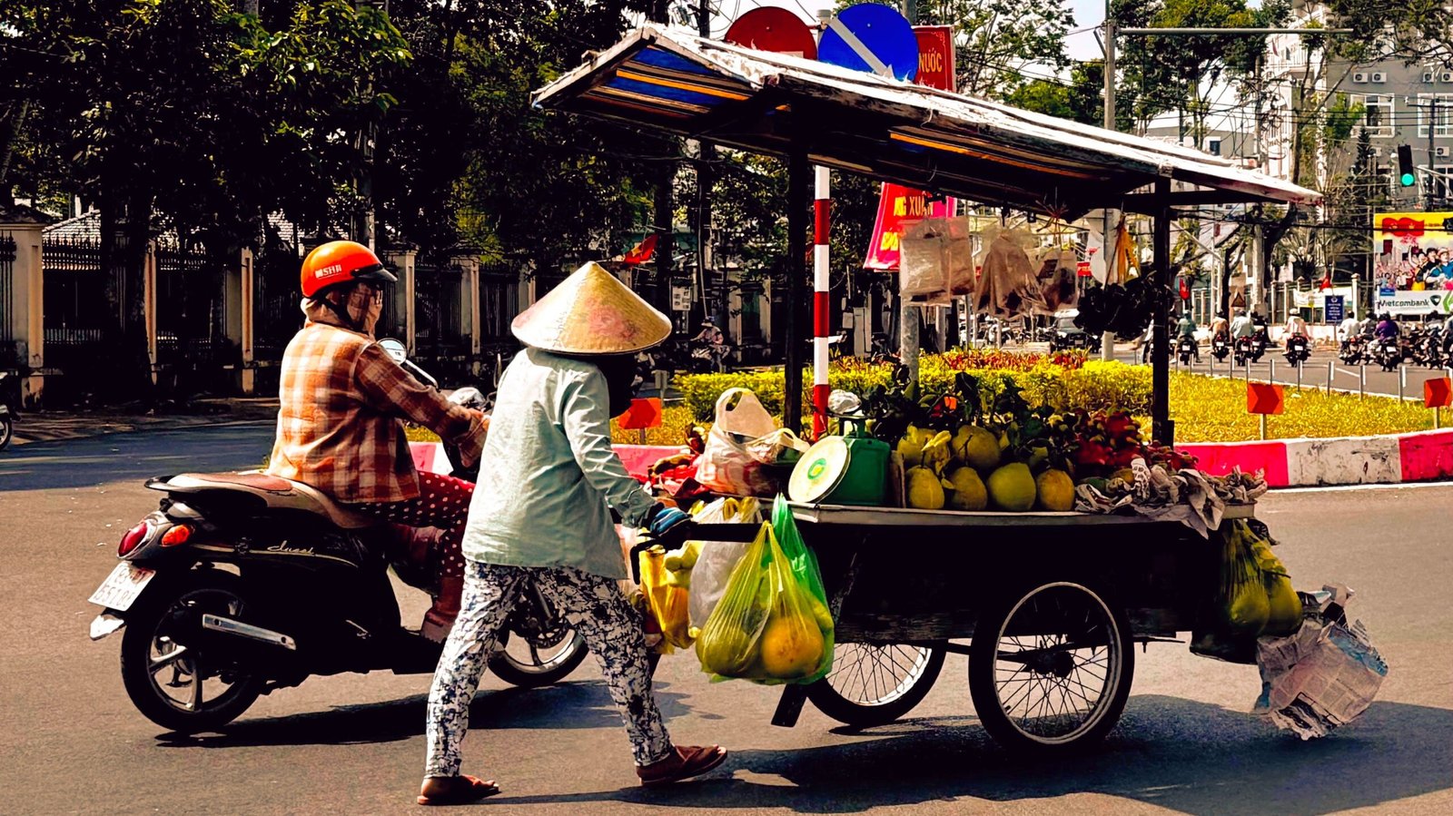 Soc Trang City street scene with fruit seller and a woman on a motorbike