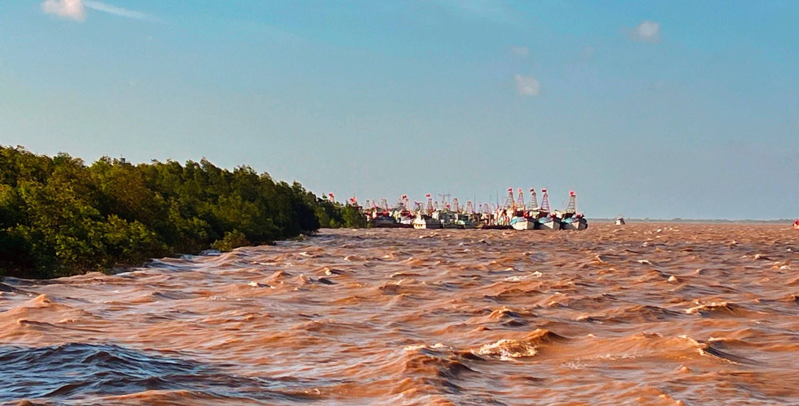 Fishing boats moored at Tran De port, Sóc Trăng, with the Hậu River running brown with sediment out