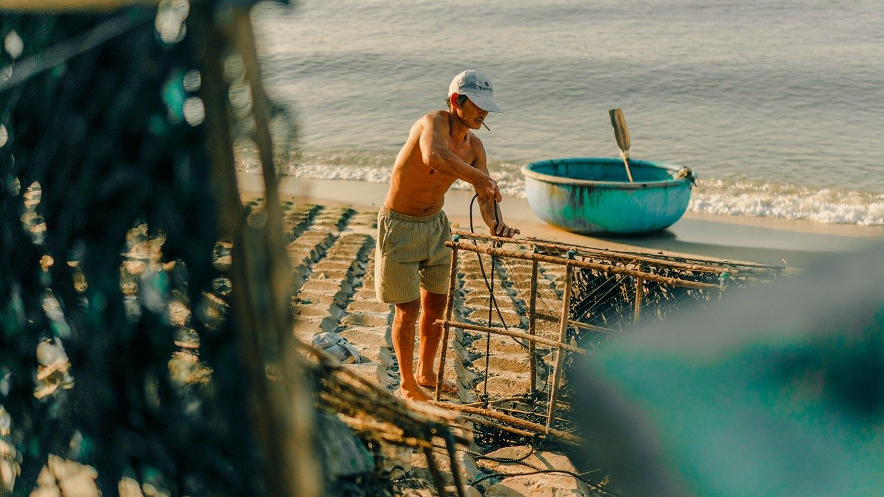 a man standing on a beach with a boat in the background